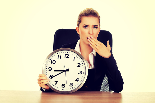 Yawning businesswoman with a clock - Foto, imagen