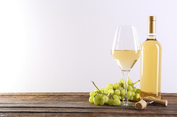 Wine and grape on wooden table against light background - Photo, image