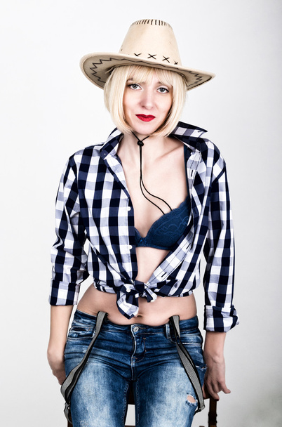 Young beautiful sexy woman in a plaid shirt jeans and a cowboy hat - Fotografie, Obrázek