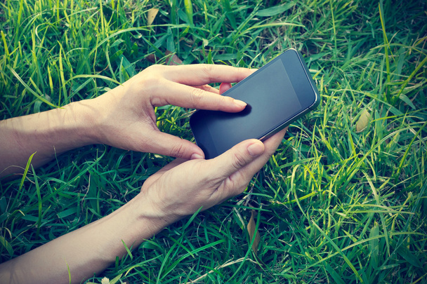žena pomocí chytrý mobilní telefon na trávě v létě - Fotografie, Obrázek