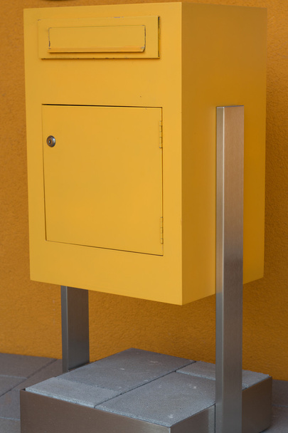 жовта поштова скринька стоїть на бетонній основі
 - Фото, зображення