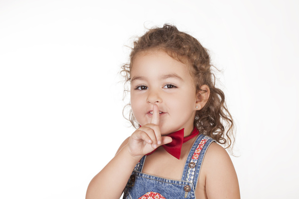 Portrait of smiling little girl with finger on lips - Valokuva, kuva