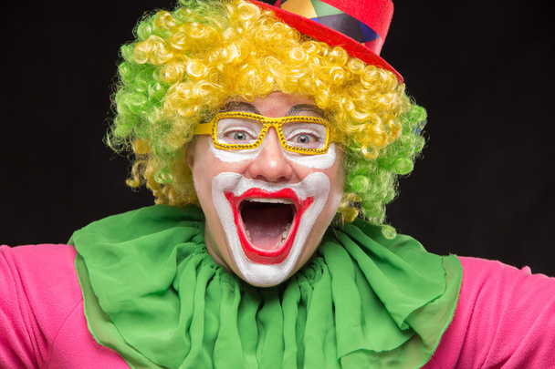 Vrolijke, grappige clown in een hoed met een groot snoep - Foto, afbeelding