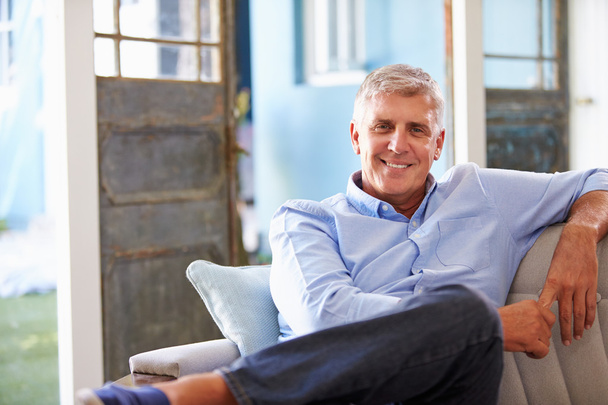 Smiling Mature Man Sitting On Sofa - Foto, Imagen