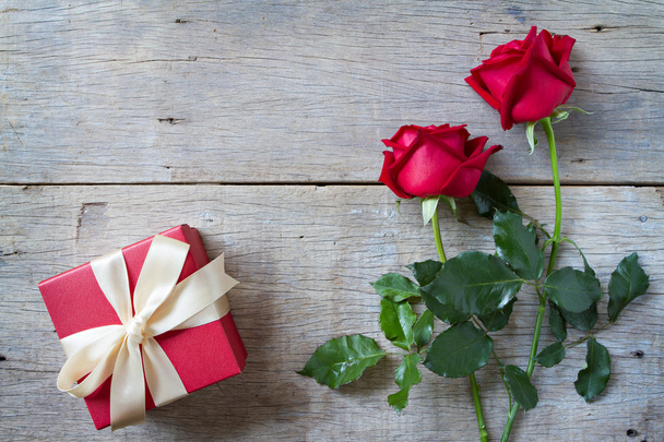 Κόκκινα τριαντάφυλλα με κόκκινη συσκευασία δώρου σε woonden φόντο. D του Αγίου Βαλεντίνου - Φωτογραφία, εικόνα
