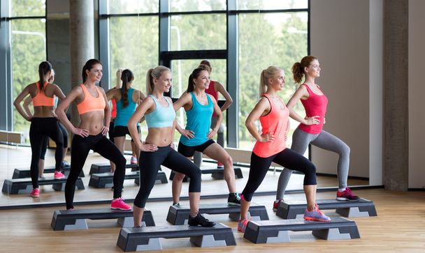 group of women working out with steppers in gym - Photo, Image