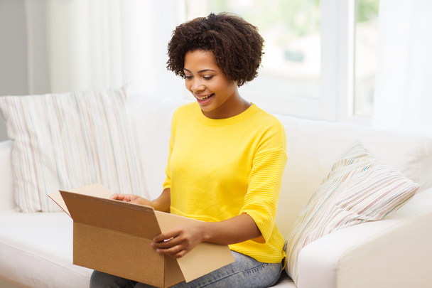 happy african young woman with parcel box at home - Foto, Bild