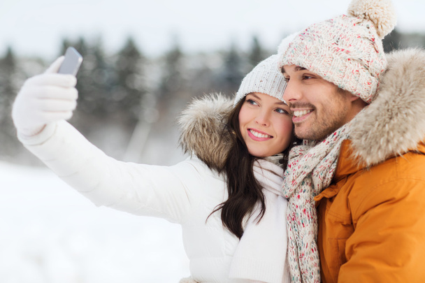 happy couple taking selfie by smartphone in winter - Foto, imagen
