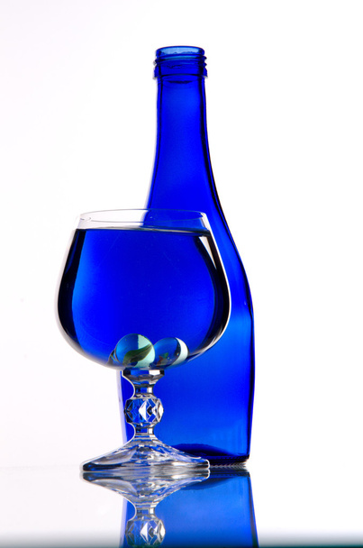 Blauwe fles en wijnglas - Foto, afbeelding