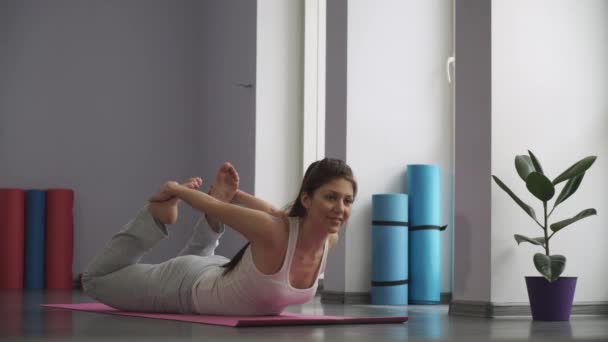 Γυναίκα που κάνει ασκήσεις για ευελιξία στο γυμναστήριο στο πάτωμα - Πλάνα, βίντεο