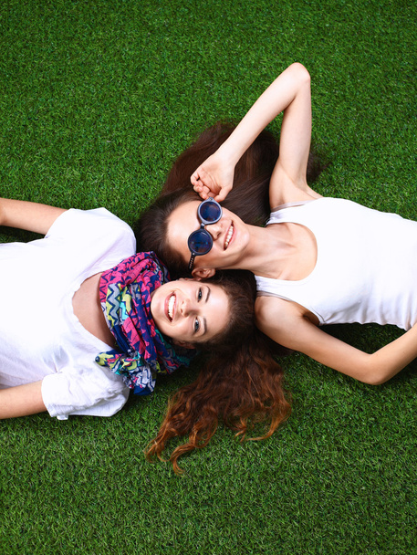 Two pretty girls lying on the fresh green grass - Valokuva, kuva