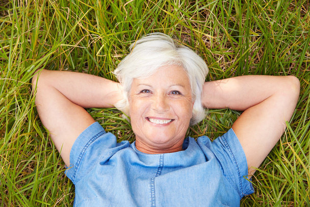 Senior woman lying on grass - Foto, imagen