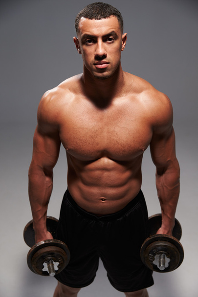Male bodybuilder holding dumbbells - Фото, изображение