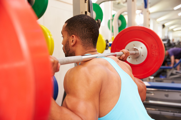 Man weightlifting barbells at a squat rack - Фото, изображение