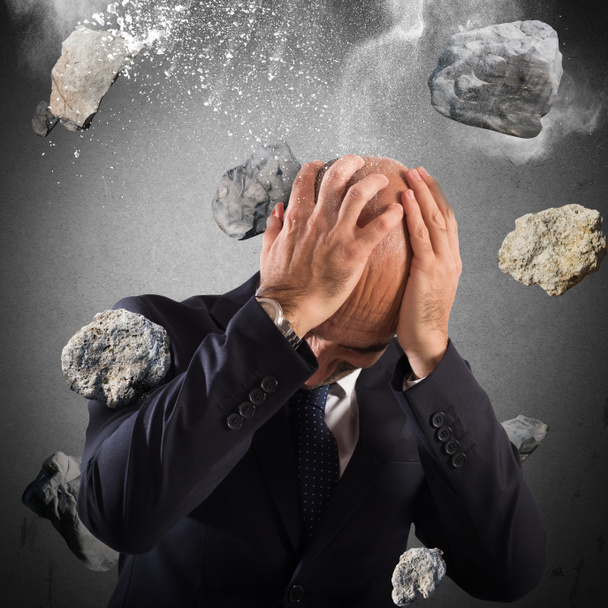 businessman protects from a boulders rain - Photo, Image