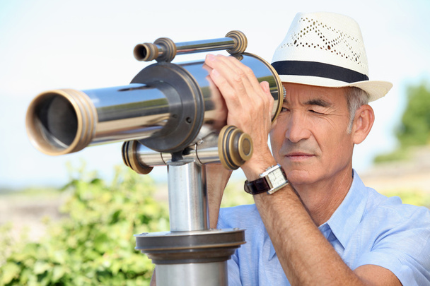 Senior man looking through a telescope - Photo, image