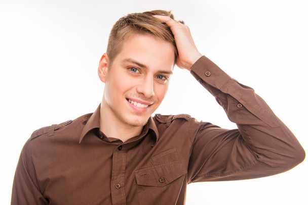 Handsome young smiling man in brown shirt touhing his hair - Foto, Bild