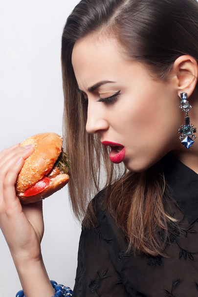  девушка ест большой гамбургер, студийное фото
 - Фото, изображение