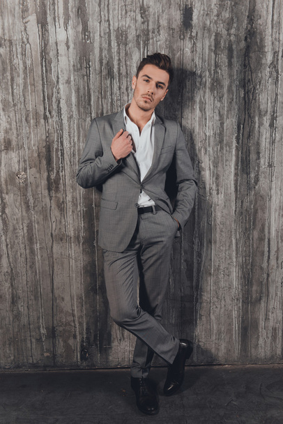 Handome man in suit on the grey background with hand in a pocket - Foto, imagen