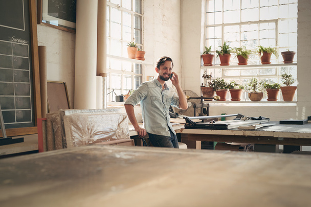 business owner on talking on phone in workshop - Фото, изображение