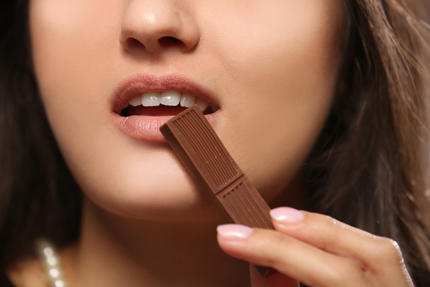 Loving chocolate woman bites bar to enjoy the taste, close up - Photo, Image