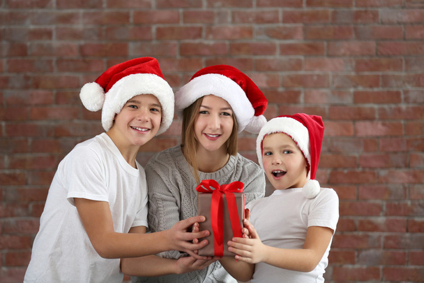 Happy cousins with gift box on brick wall background - Fotoğraf, Görsel