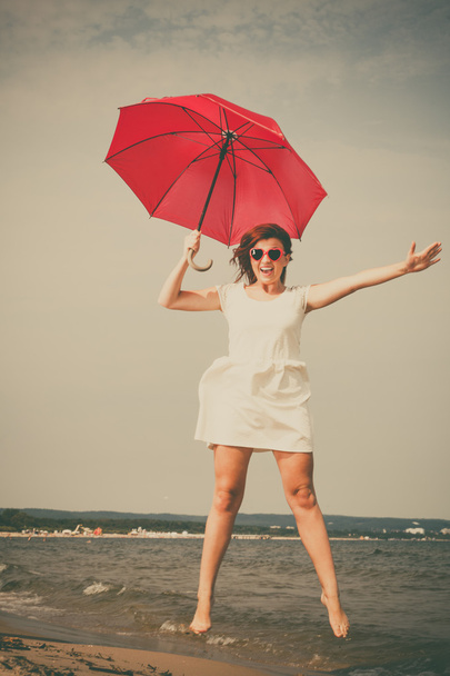 girl jumping with red umbrella - Фото, изображение