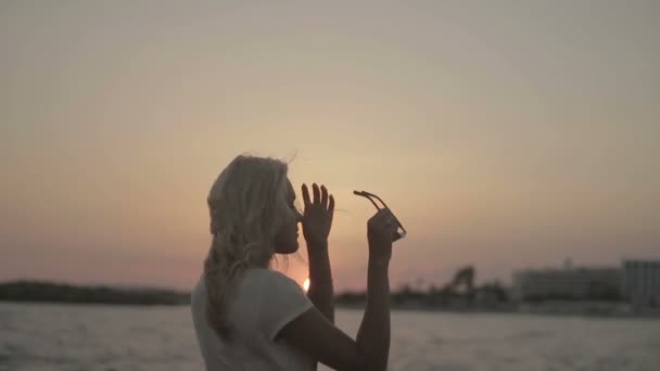 Ρομαντικό κορίτσι στο ηλιοβασίλεμα στο φόντο στη θάλασσα - Πλάνα, βίντεο
