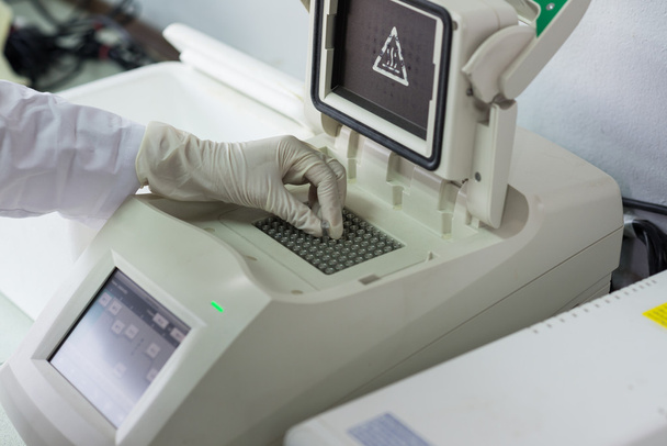 Mano con guantes que entra en la muestra en el dispositivo de laboratorio
 - Foto, imagen