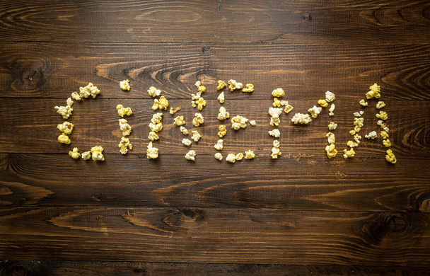 Konceptuální záběr slovo kino napsal popcorn na dřevěných zpět - Fotografie, Obrázek