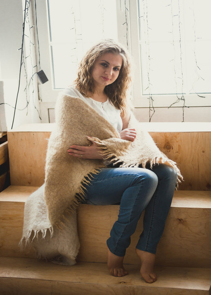 Toned photo of curly girl covering in warm scarf on windowsill - Foto, Bild