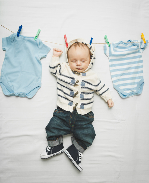 menino pequeno em jeans pendurado no cabo ao lado de roupas de secagem
 - Foto, Imagem