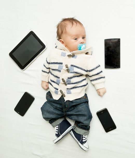 Söpö pieni poika makaa sängyssä digitaalisten tablettien ja älypuhelimen kanssa
 - Valokuva, kuva