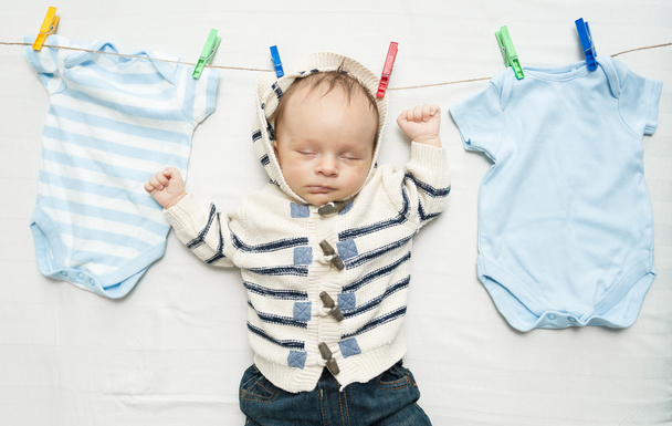 cute baby boy hanging on clothesline next to drying clothes - Photo, Image