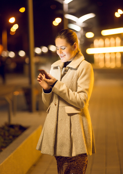 young woman using smartphone on street at night - Foto, Imagem