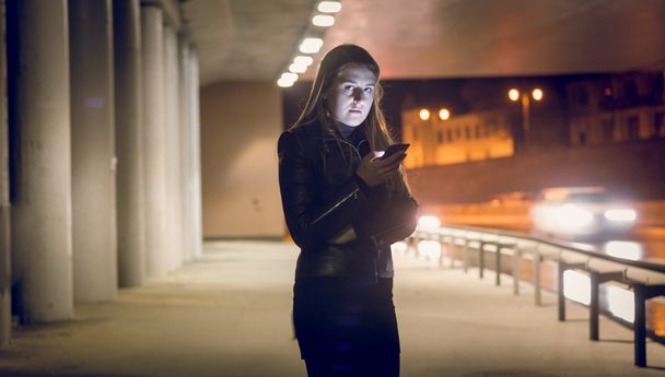 solo mujer escribiendo mensaje de texto en la calle oscura
 - Foto, imagen
