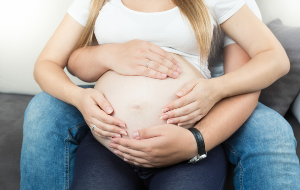 pregnant couple holding hands on big belly - Valokuva, kuva