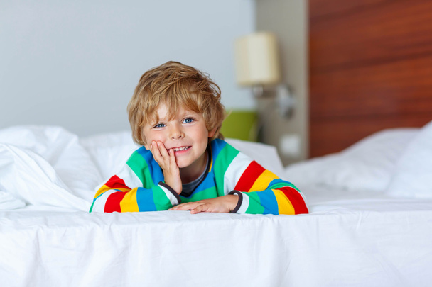 entzückendes Kind Junge nach dem Schlafen in seinem weißen Bett mit Spielzeug - Foto, Bild