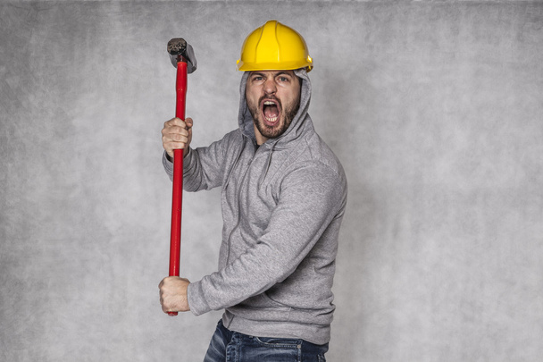builder on a grey background, holding a hammer and shouting - Foto, immagini