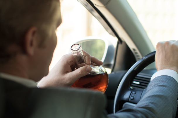 Driver drinks alcohol driving a car - Foto, Imagen