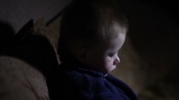 kleine jongen zit op de Bank in de donkere kamer - Video