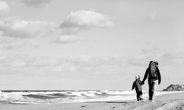 冬のビーチの上を歩いて小さな子供とのお父さん. - 写真・画像