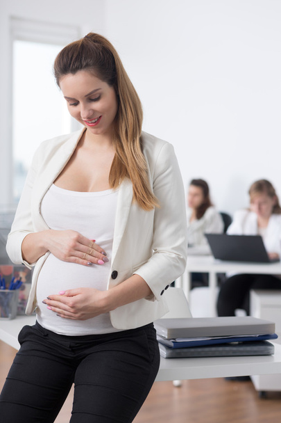 Businesswoman touching her pregnant tummy - Фото, изображение