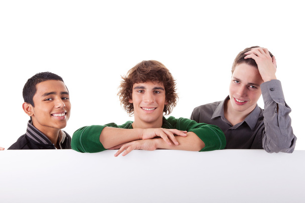 Happy three young, of different colors man with a white board, isolated on a white background - Photo, Image