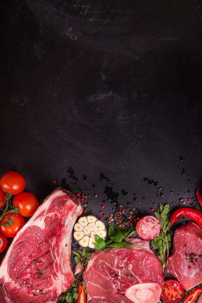 Стейки из сырого мяса на тёмном фоне, готовые к жарке
 - Фото, изображение