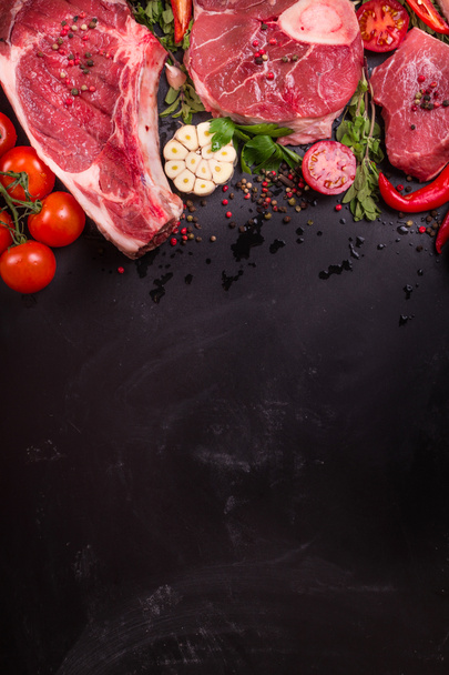 Raw meat steaks on a dark background ready to roasting - Photo, Image