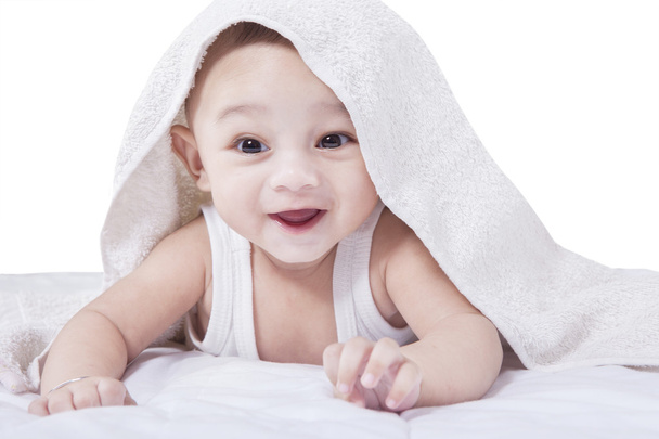 タオルの下で横になっているうれしそうな赤ちゃん - 写真・画像