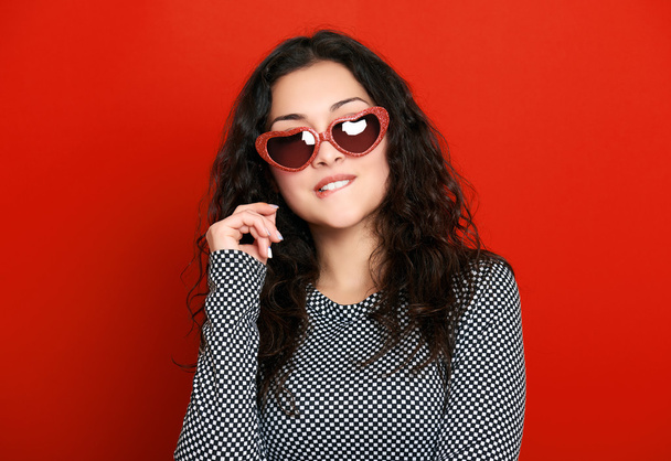 beautiful girl glamour portrait on red in heart shape sunglasses, long curly hair - Photo, Image