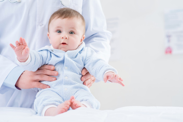 Professional pediatrician holding infant - Zdjęcie, obraz