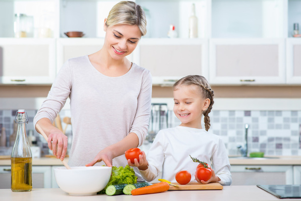 Mother  and her daughter cooking in the kitchen - Фото, изображение